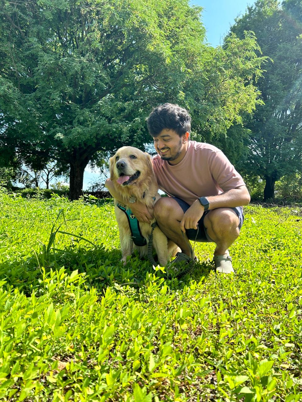 Gokul sitting with a golden retriever in a park